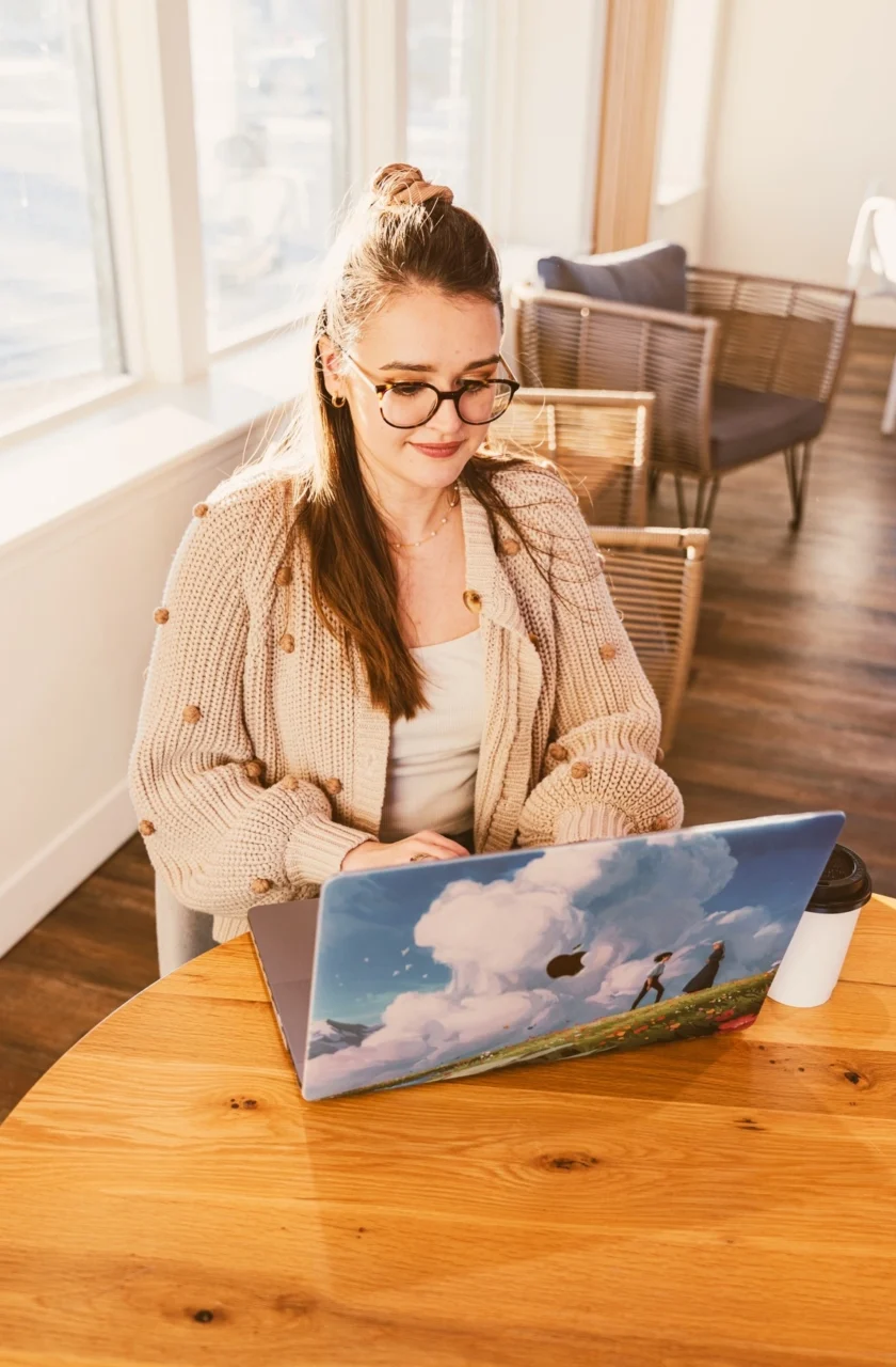 Cross & Crown employee sitting at a table with a laptop