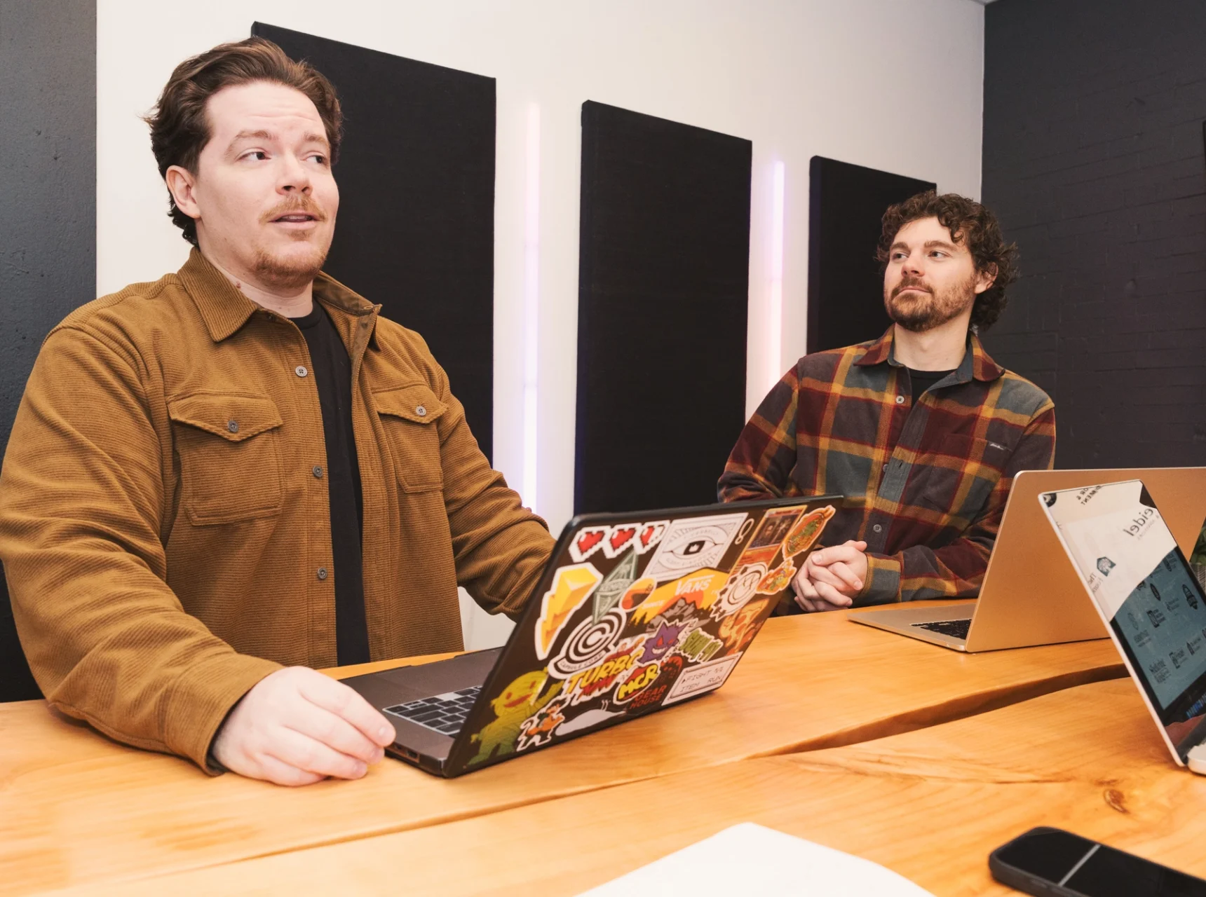 Cross & Crown employees talking and standing by a table with laptops
