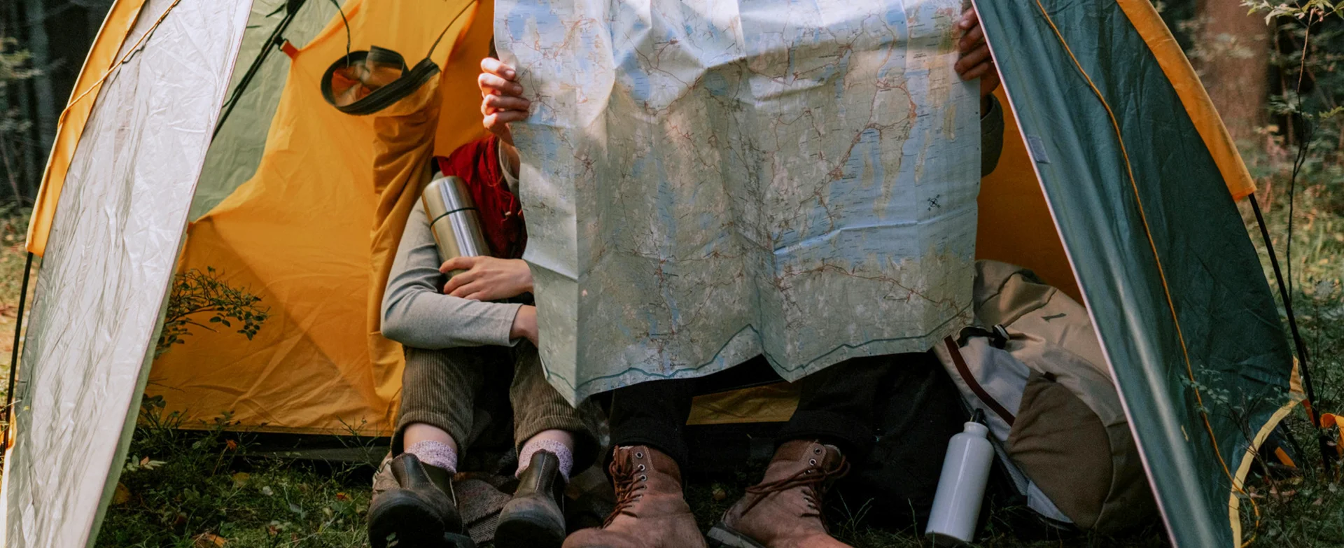 People holding map and sitting in tent