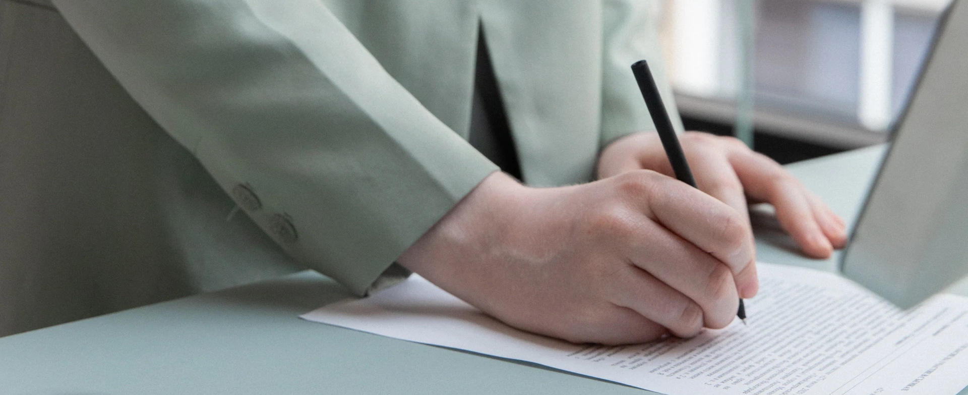 Accountant in green blazer writing with a pen.