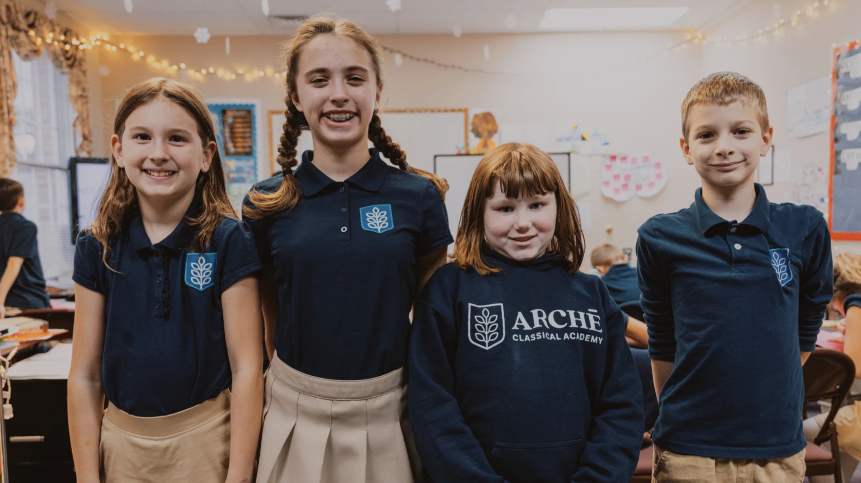 Marketing strategies for school enrollment. Four students in a class room smiling for a photo.