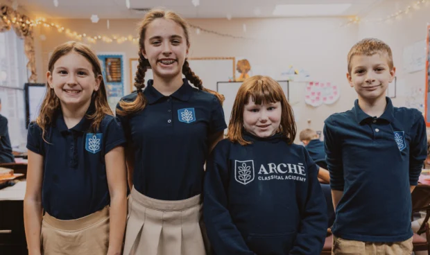 Marketing strategies for school enrollment. Four students in a class room smiling for a photo.