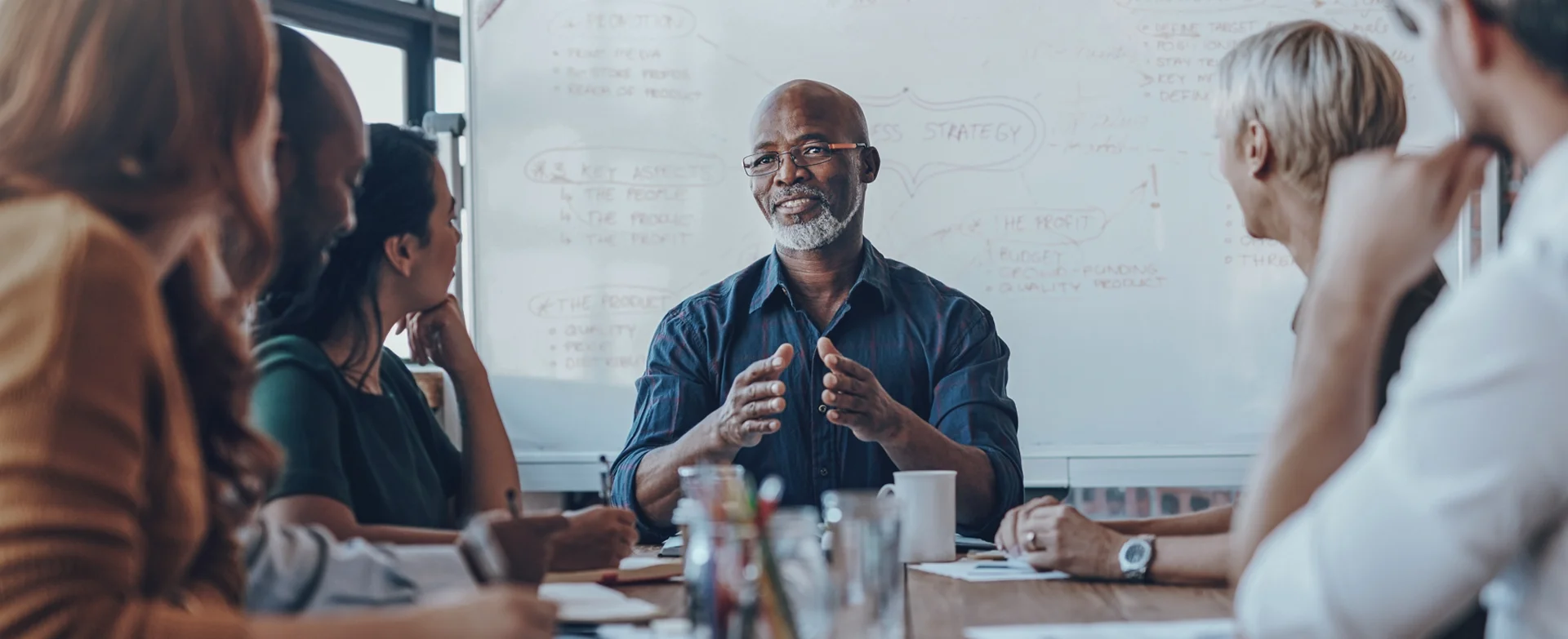 A group of people sit and listen at a meeting table.