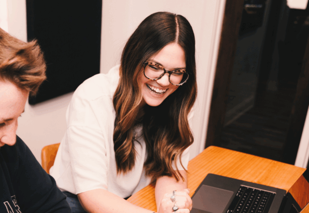 two people sitting at a table with laptops