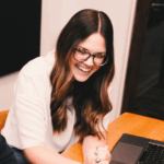 two people sitting at a table with laptops