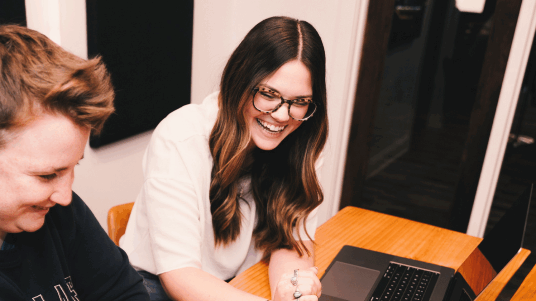 two people sitting at a table with laptops