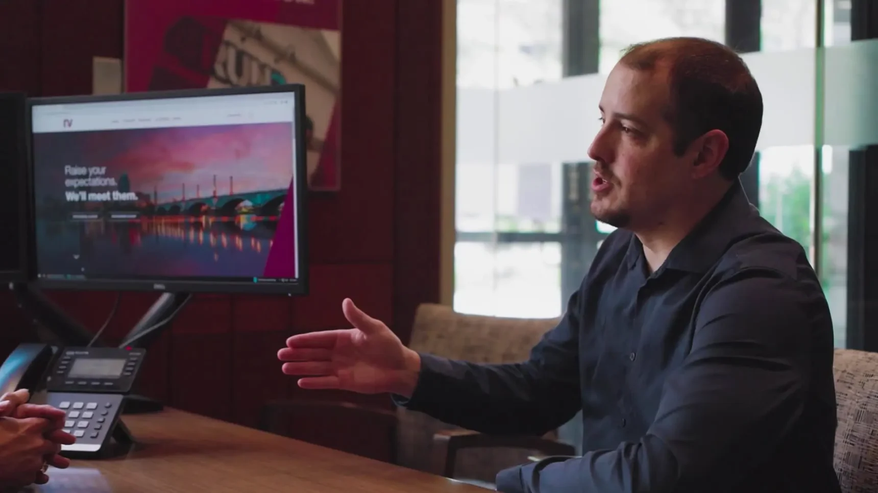 A man talking in front of the desk and a computer