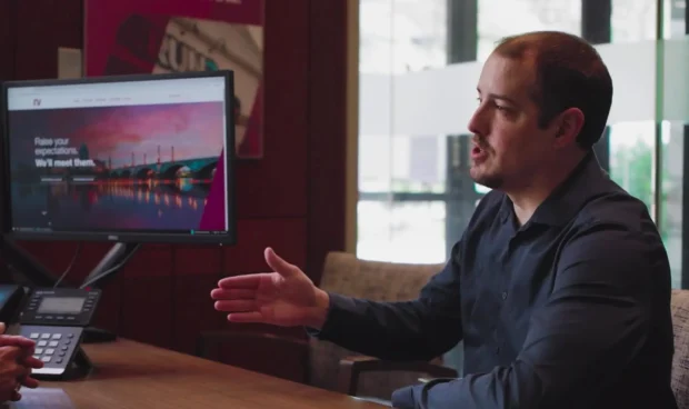 A man talking in front of the desk and a computer