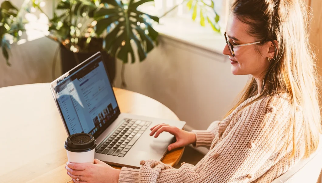 A woman smiling and looking at a laptop