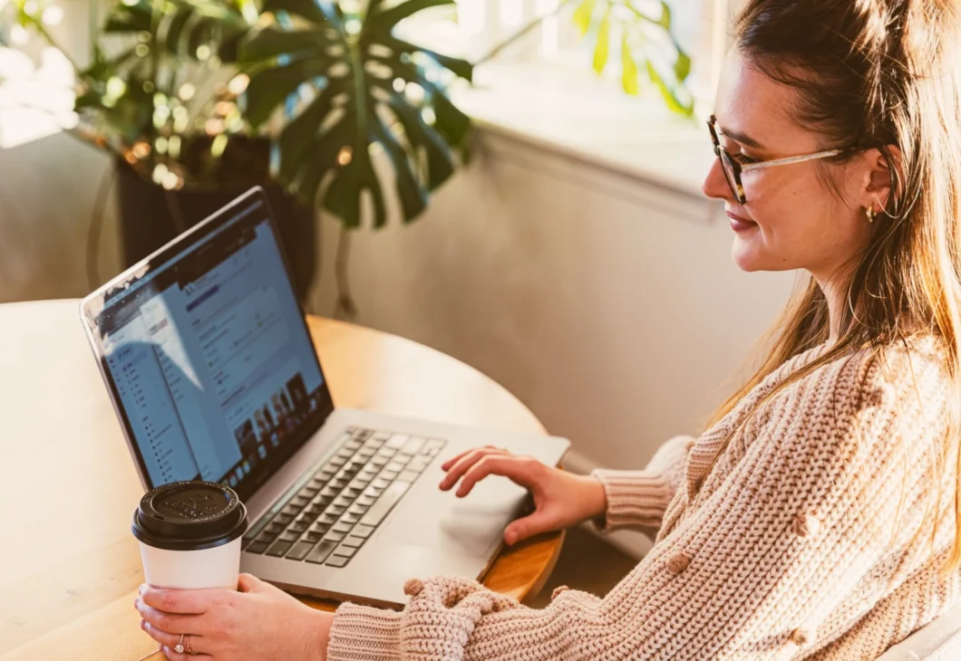A woman smiling and looking at a laptop