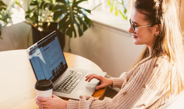 A woman smiling and looking at a laptop