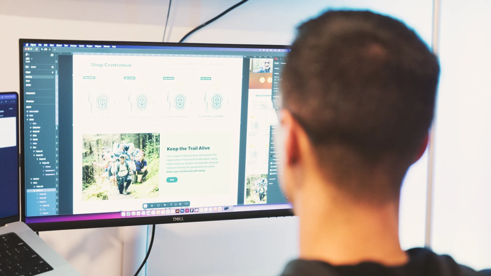 A person looks at a computer screen displaying a website with images of people hiking and text about graphics