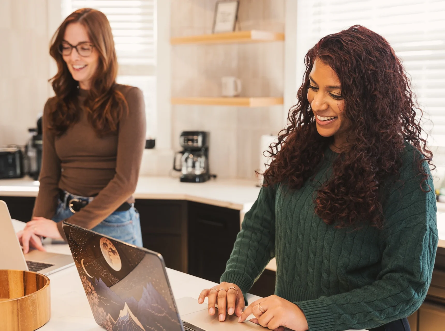 Cross & Crown employees standing by the counter looking at laptop and smiling